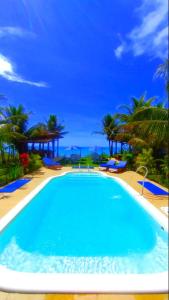 a swimming pool with blue water and palm trees at Pousada Azul com vistas maravilhosas in Cumuruxatiba