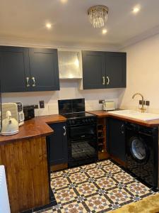 a kitchen with black cabinets and a black dishwasher at Captain's Nook, Luxurious Victorian Apartment with Four Poster Bed and Private Parking only 8 minutes walk to the Historic Harbour in Brixham