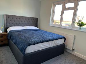 - une chambre avec un lit avec une couette bleue et 2 fenêtres dans l'établissement Modern 3 Bed home in Grantham, à Grantham