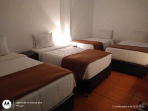 um quarto com três camas num quarto de hotel em Ortega's House Machupicchu em Machu Picchu