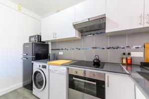 a kitchen with white cabinets and a washer and dryer at Magnifique duplex Cosy Gare Terrasse 4Pers in Argenteuil