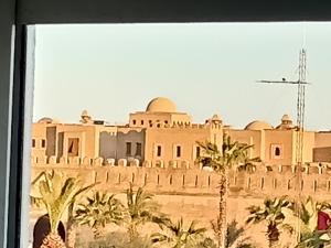 Blick auf ein Gebäude in der Wüste mit Palmen in der Unterkunft IMMEUBLE BRINI in Kairouan
