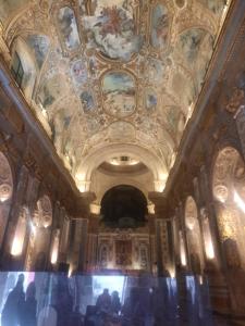 une chambre avec un plafond orné de peintures. dans l'établissement casa del caravaggio, à Naples