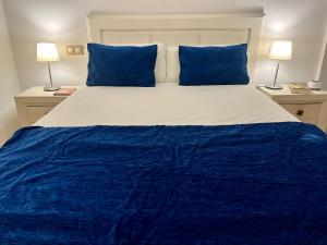 a blue and white bed with blue pillows and two lamps at Apartamento Las Canteras in Las Palmas de Gran Canaria