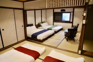 a small room with two beds and a table at 動物園前駅まで徒歩5分/通天閣近く/道頓堀エリアまで電車3分/大阪グルメ旅行に最適！ in Osaka
