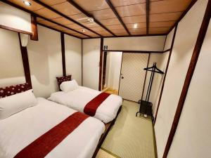 a small room with two beds and a mirror at 動物園前駅まで徒歩5分/通天閣近く/道頓堀エリアまで電車3分/大阪グルメ旅行に最適！ in Osaka