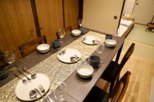 a long table with white plates and silverware on it at 動物園前駅まで徒歩5分/通天閣近く/道頓堀エリアまで電車3分/大阪グルメ旅行に最適！ in Osaka