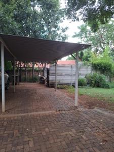 a pavilion with a roof on a brick driveway at Die Eend Studio in Centurion