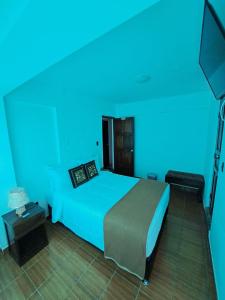 a blue room with a bed and a television at Ortega's House Machupicchu in Machu Picchu