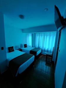 Habitación de hotel con 2 camas y luz azul en Ortega's House Machupicchu en Machu Picchu
