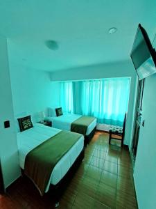 a hotel room with two beds and a television at Ortega's House Machupicchu in Machu Picchu