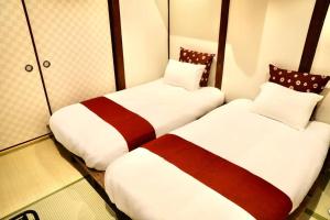 two beds in a hotel room with white and red at 動物園前駅まで徒歩5分/通天閣近く/道頓堀エリアまで電車3分/大阪グルメ旅行に最適！ in Osaka