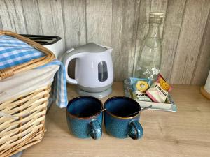 two blue mugs sitting on a counter with a coffee maker at Seaside Homestay - Ensuite twin room with Kitchenette in Paignton