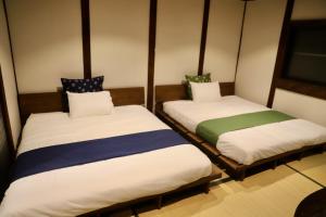 two twin beds in a small room with at 動物園前駅まで徒歩5分/通天閣近く/道頓堀エリアまで電車3分/大阪グルメ旅行に最適！ in Osaka