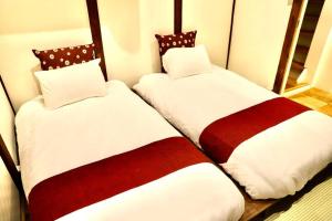 two beds sitting next to each other in a room at 動物園前駅まで徒歩5分/通天閣近く/道頓堀エリアまで電車3分/大阪グルメ旅行に最適！ in Osaka