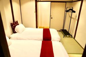 a bedroom with two beds with white and red at 動物園前駅まで徒歩5分/通天閣近く/道頓堀エリアまで電車3分/大阪グルメ旅行に最適！ in Osaka
