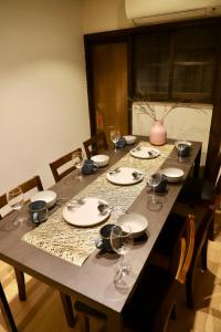 a long wooden table with plates and wine glasses at 動物園前駅まで徒歩5分/通天閣近く/道頓堀エリアまで電車3分/大阪グルメ旅行に最適！ in Osaka