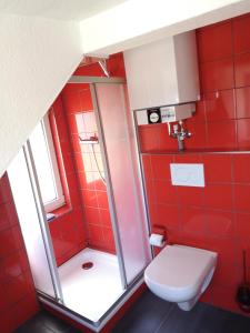 a red bathroom with a toilet and a shower at Stranddüne in Cuxhaven +4 photos