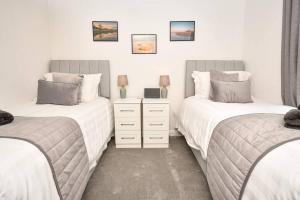 a bedroom with two twin beds and a dresser at The Hideaway - Luxury 2 bedroom ground floor apt in Warkworth