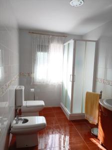 La salle de bains blanche est pourvue de toilettes et d'un lavabo. dans l'établissement Mi Carmela, à Cenes de la Vega