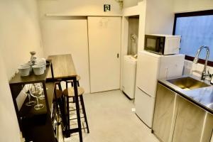 a kitchen with a white refrigerator and a counter top at 動物園前駅まで徒歩5分/通天閣近く/道頓堀エリアまで電車3分/大阪グルメ旅行に最適！ in Osaka