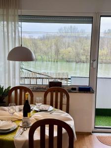 a dining room table with a view of a river at Stan na dan Kej Una in Bosanska Dubica