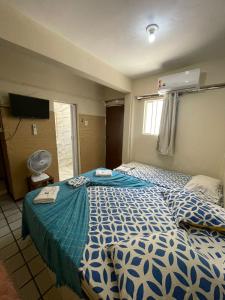 Schlafzimmer mit einem blauen und weißen Bett und einem Ventilator in der Unterkunft Hotel Paradiso in João Pessoa