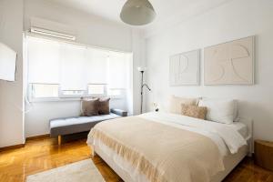 a white bedroom with a large bed and a chair at Supreme Aprt Syntagma Kolonaki in Athens