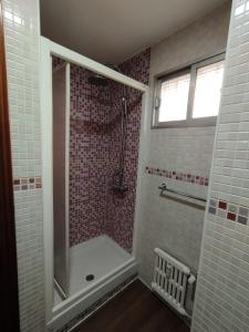 Una ducha a ras de suelo en un baño con azulejos blancos. en Piso luminoso en Madrid Rio, en Madrid