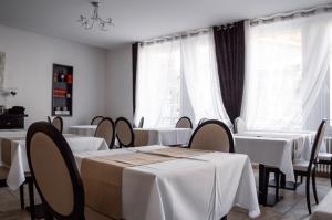 un restaurant avec des tables blanches, des chaises et des fenêtres dans l'établissement Hôtel Le Tivoli, à Sisteron