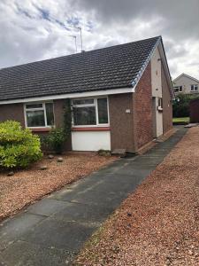 a brick house with a sidewalk in front of it at St Andrews Bungalow in Fife