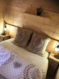 a bedroom with a bed with a wooden wall at Le chalet de DOMY in Granges-sur-Vologne