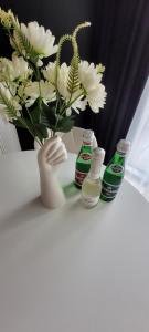 a vase with white flowers and soda bottles on a table at Hanza Tower Apartament 306, BASEN, SAUNA, JACUZZI in Szczecin