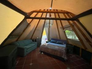 a attic room with a bed and a couch at Glamping El Establo in San Francisco