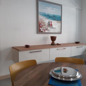 una sala da pranzo con tavolo e un dipinto sul muro di Loft a Marconia a Marconia