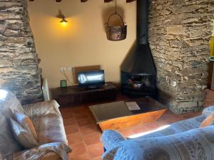 a living room with a stone fireplace and a tv at Can Bonada in El Serrat