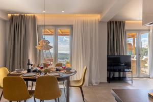 a dining room with a table and chairs and a television at Eartha Horizon Villas Naxos in Naxos Chora