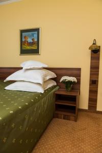 a bedroom with a bed with white pillows and a table at Hotel Lyra in Oradea