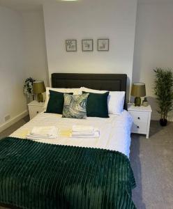 a bedroom with a large bed with green sheets and pillows at 2-bedroom house in Cheltenham town centre in Cheltenham