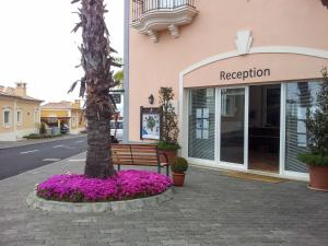 un edificio con un árbol y flores púrpuras delante de un banco en Palheiro Village - Golf, Gardens & Spa en Funchal