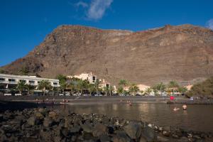 people on a beach with a mountain in the background at Apartamentos Charco del Conde in Valle Gran Rey