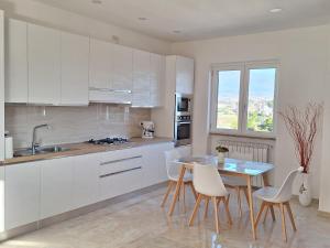 een keuken met witte kasten en een tafel en stoelen bij Mimì Luxury Apartment in Pompei