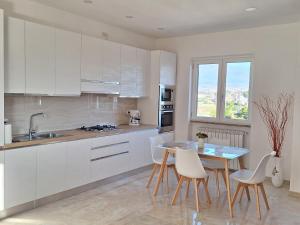 Una cocina con gabinetes blancos y una mesa y sillas. en Mimì Luxury Apartment, en Pompeya 19 fotos más