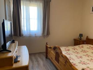 1 dormitorio con 1 cama, TV y ventana en Tündér Pension en Mogyoród