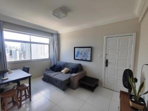 a living room with a couch and a table and a window at 1 Quarto e Sala amplo 47 m2 Vista Mar in Salvador