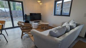 a living room with a couch and a television at Les Gîtes du Grain Clos in Conteville