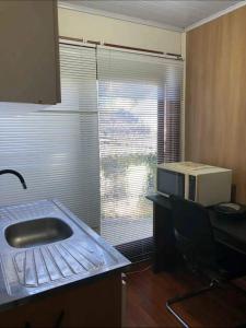 une cuisine avec évier et une fenêtre avec four micro-ondes dans l'établissement Suíte aconchegante, à Santa Cruz do Sul
