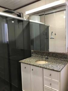 La salle de bains est pourvue d'un lavabo et d'un grand miroir. dans l'établissement Suíte aconchegante, à Santa Cruz do Sul