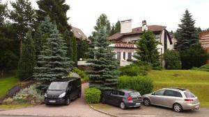 dos autos estacionados en un estacionamiento frente a una casa en Pokoje Gościnne Akacja, en Polanica-Zdrój