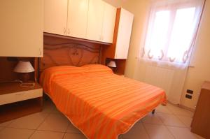 a bedroom with a bed with an orange striped sheet at Residence Zodiaco in San Benedetto del Tronto